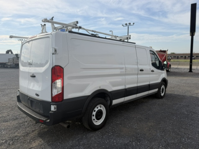 Ford TRANSIT/Transit-style utility van in service use with ladder rack on roof, rear doors, side profile visible.