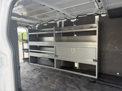 Ford Transit-250 cargo van interior with metal shelving and partition, viewed from rear right side; no visible text on shelves.