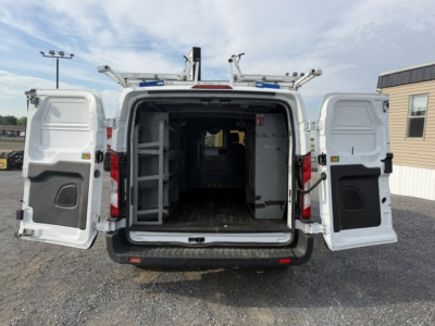 Ford Transit/Transit-style cargo van interior showing empty cargo area with side shelves and hooks, rear double doors open.