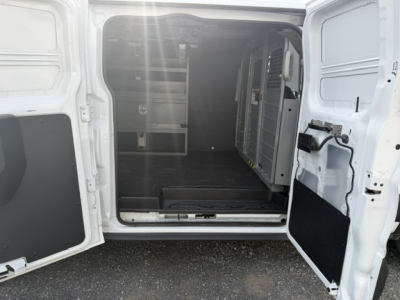 Ford Transit 250 van cargo area with rear doors open, view of empty metal shelving and partition inside.