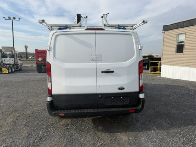 Ford Transit 250 van rear view showing cargo doors, rear bumper, and roof ladder racks. No visible text or labels clearly legible.