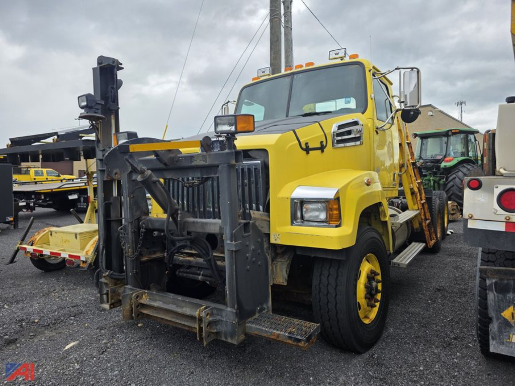 Front view of a yellow Western Star 4700 SF cab and chassis with a heavy-duty push bumper and crane attachment visible.