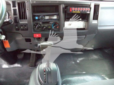 Isuzu NPR HD truck dashboard showing controls, gauges, and a rectangular red-lit diagnostic panel above the center console with blank white label area.