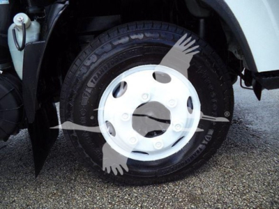 Isuzu NPR HD truck wheel and front fender area showing tire and white steel wheel with hub cover; part of front wheel well visible.