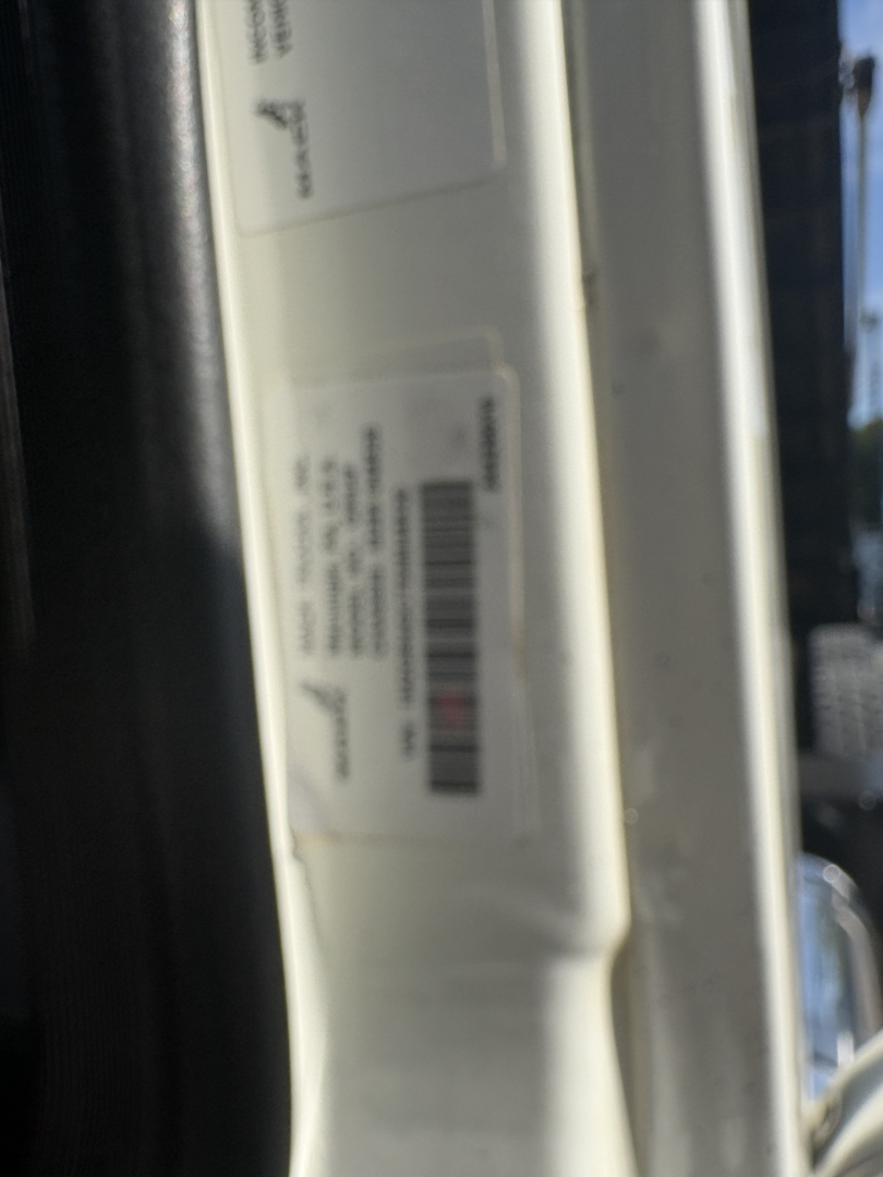 View of a vehicle door jamb with a white label containing barcodes and text.