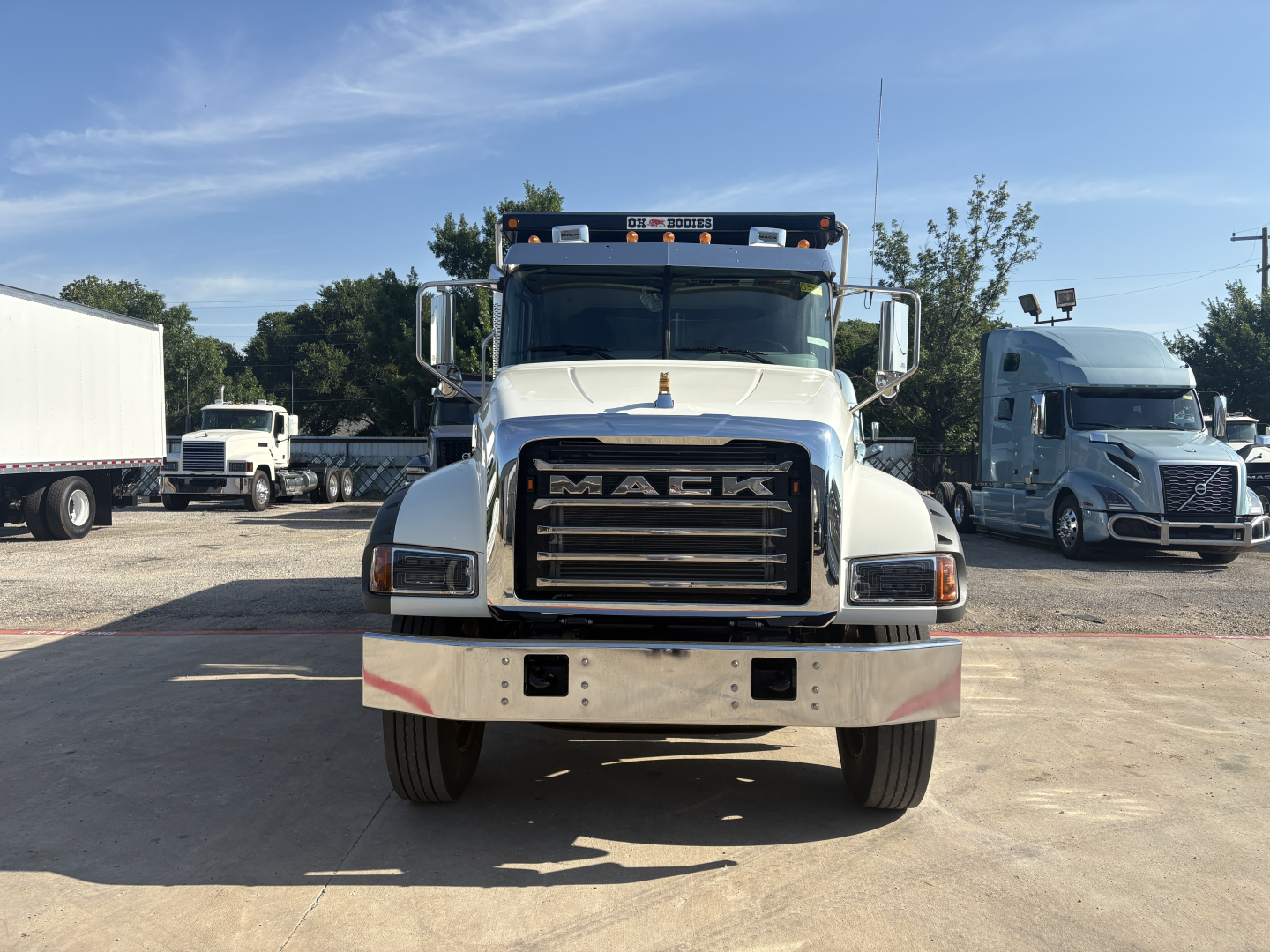 Truck front view showing Mack grille and bumper in-service with clear headlights and side mirrors.
