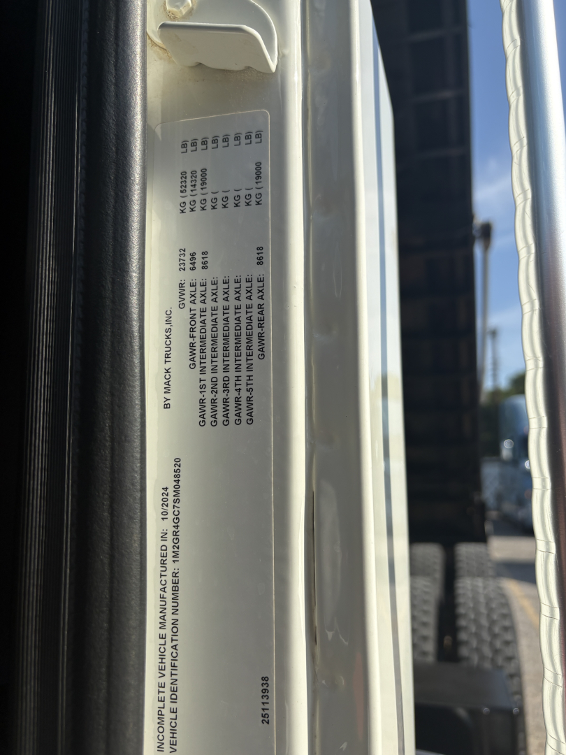 Tag with vehicle specification text on Mack GR64F side, listing model, weights, and manufacturing details.