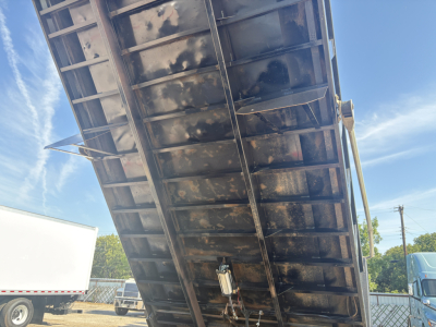 Dump truck bed underside showing metal frame and hydraulic mechanism in view, grime on surfaces.