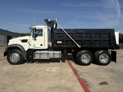 Truck side view of a Mack GR64F dump truck with a white cab and black dump bed.