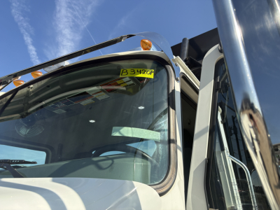 Mack GR64F truck front cab window with B3420P stock tag visible on windshield, part of dump truck in service, VIN 1M2GR4GC7SM048520.