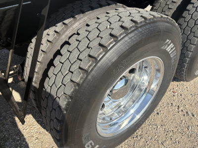 Mack GR64F truck wheel and tire showing heavy tread and polished chrome rim.