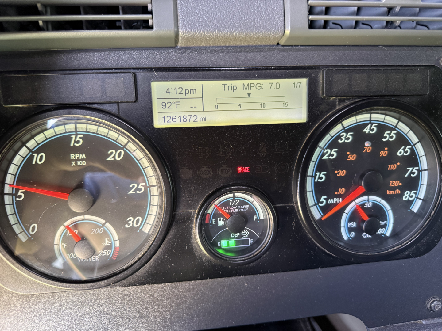 Dashboard of a Freightliner Cascadia evolution showing gauges and digital display with trip MPG 7.0, odometer 1261872 miles, and various indicator dials.