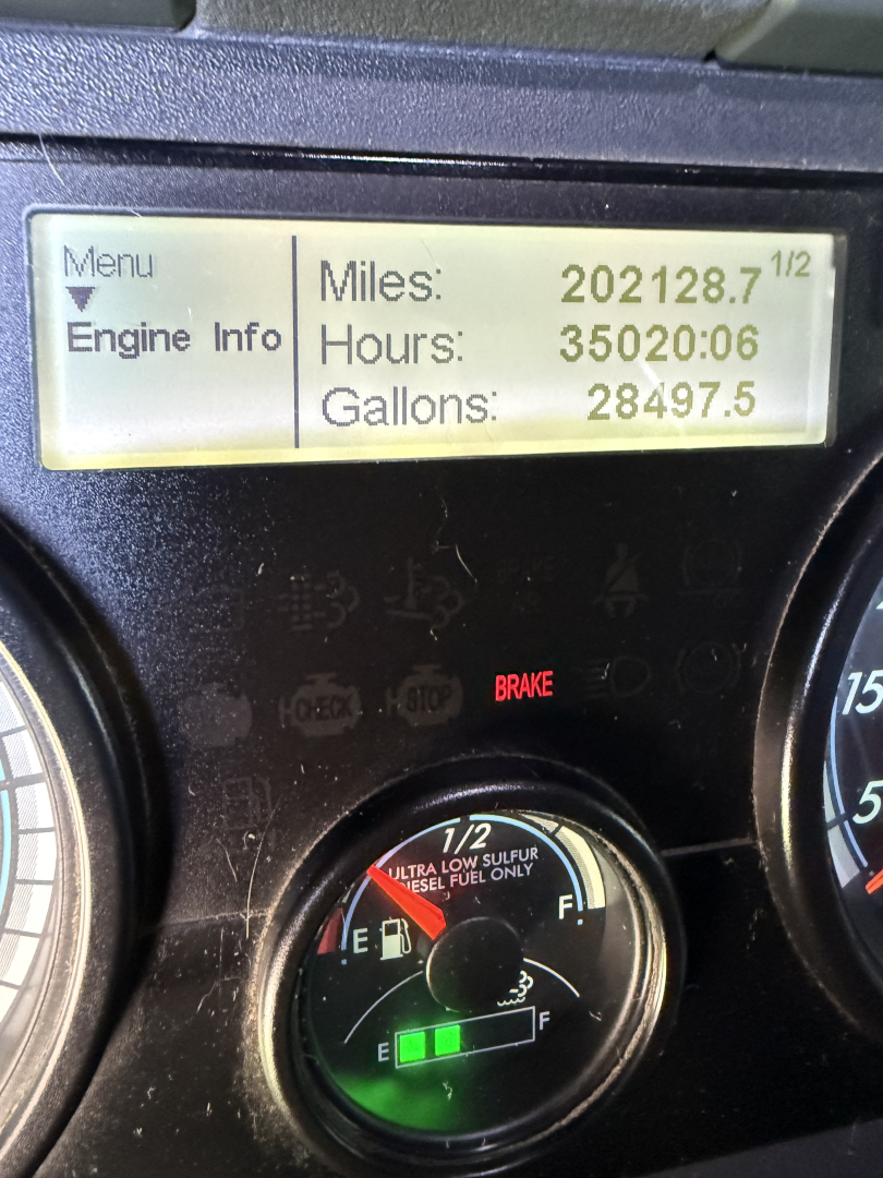 Dashboard of a 2016 Freightliner Cascadia Evolution showing odometer and fuel gauge readings: Miles 202128.7, Hours 35020:06, Gallons 28497.5; brake warning light visible.