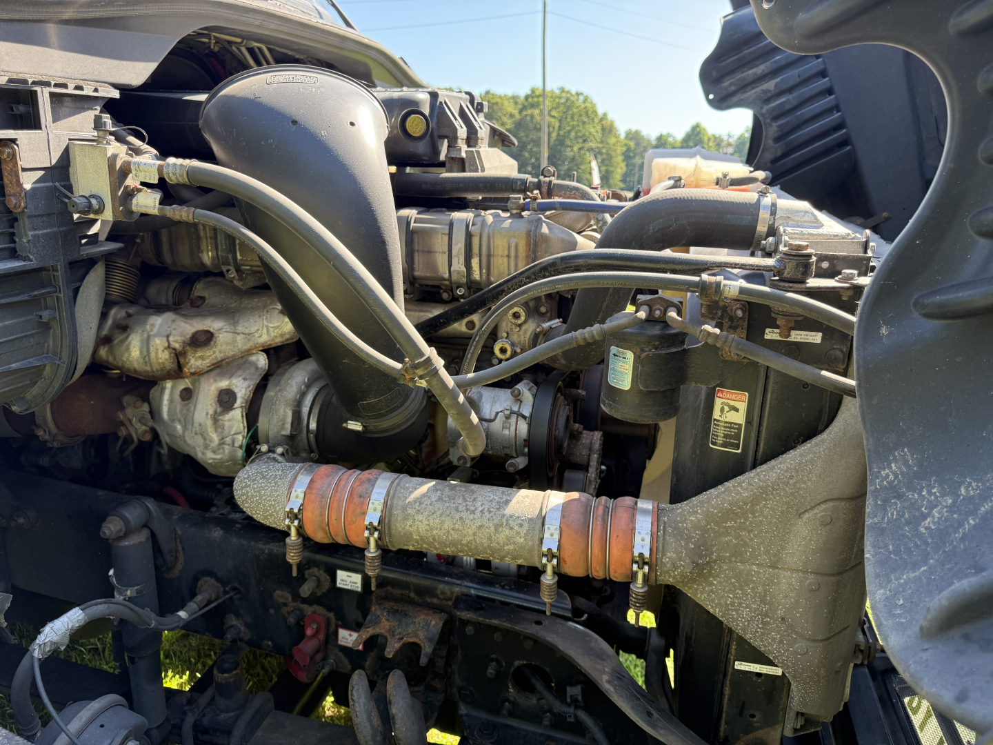 Truck engine bay of a 2016 Freightliner Cascadia Evolution showing fuel lines, coolant hoses, turbocharger, belts, and various engine components.