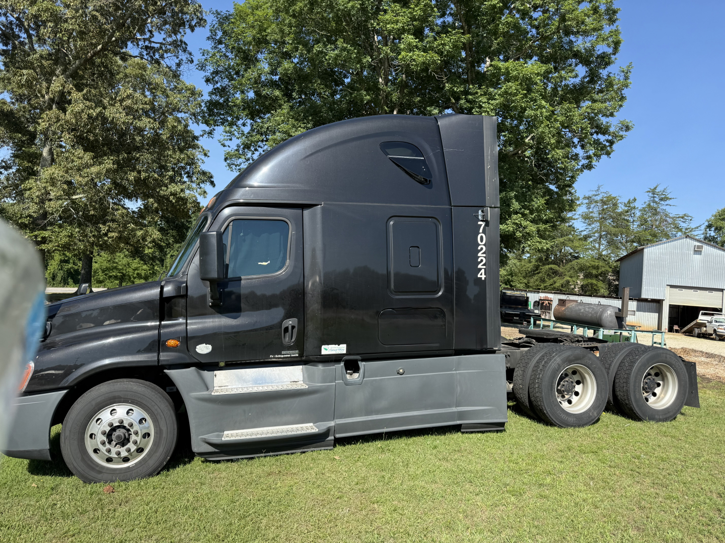 Truck cab side view showing 2016 Freightliner Cascadia Evolution sleeper, dark gray, with 3-axle tandem rear and chrome fuel tanks.