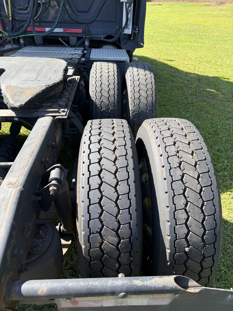 Rear triple-axle truck chassis with two right-side tires visible, Freightliner Cascadia evolution part of a used conventional sleeper tractor.