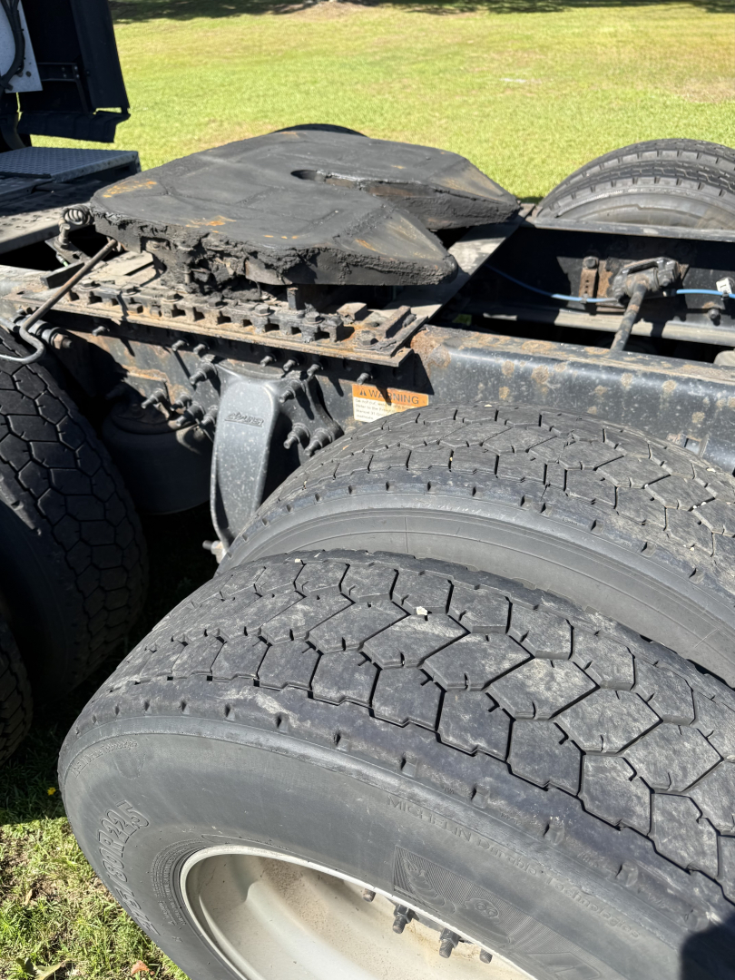 Tractor-trailer rear chassis with dual rear axles and worn fifth-wheel hitch showing tire tread and grime.