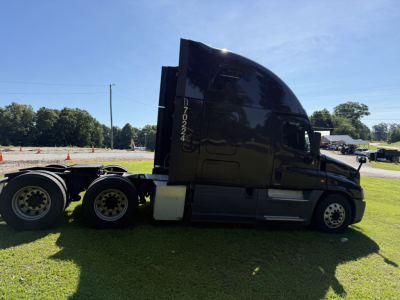 Tractor unit side view of a black 2016 Freightliner Cascadia Evolution conventional sleeper with triple rear axles and tall sleeper cab.