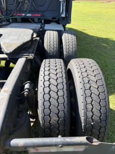 Rear triple-axle truck chassis with two right-side tires visible, Freightliner Cascadia evolution part of a used conventional sleeper tractor.
