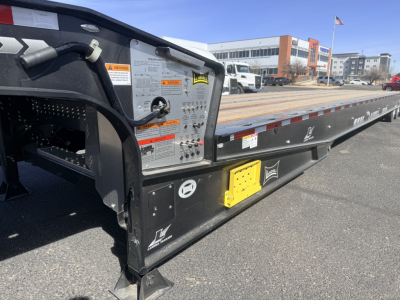 Landoll 440B-53 40 Ton traveling axle lowboy trailer side with control panel and decals showing warning labels and yellow access panel.