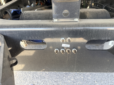 Front view of Landoll 440B-53 lowboy trailer hitch area showing mounting bolts and identification label, oil residues, and structural frame.