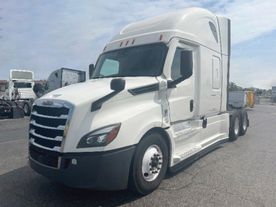 Truck cab of a white Freightliner Cascadia126 semi-truck, front three-quarter view with sleeper cab, chrome grille, black bumper, and side steps.