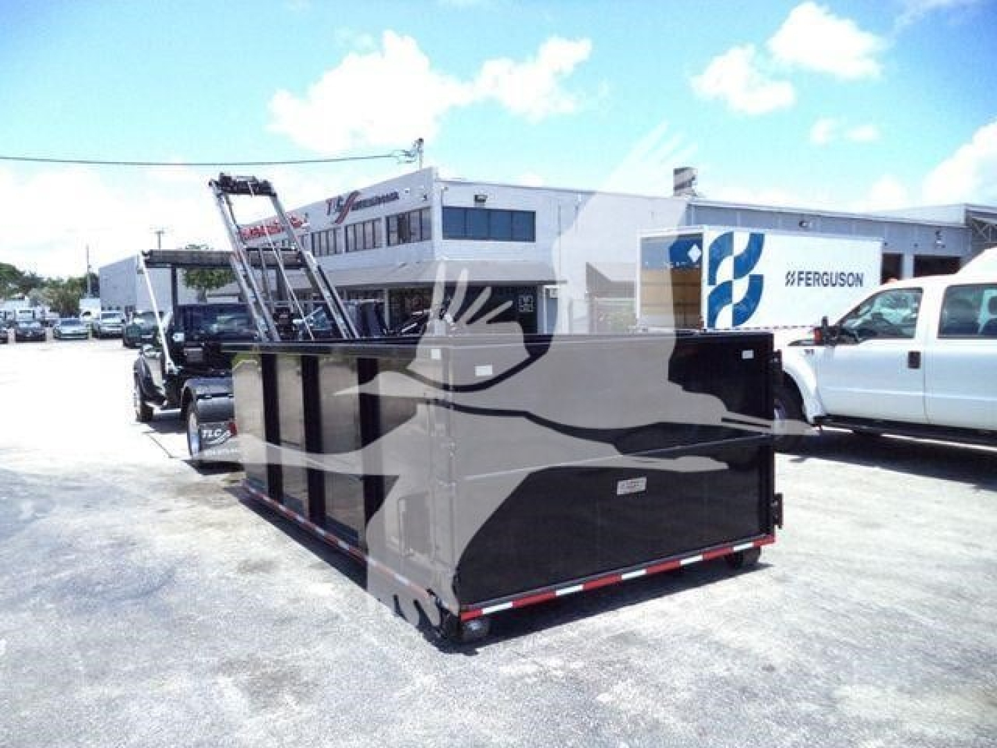 Ram 5500 dump-bed hooklift truck in a dealership lot with trailer side panels and loading ramp visible.