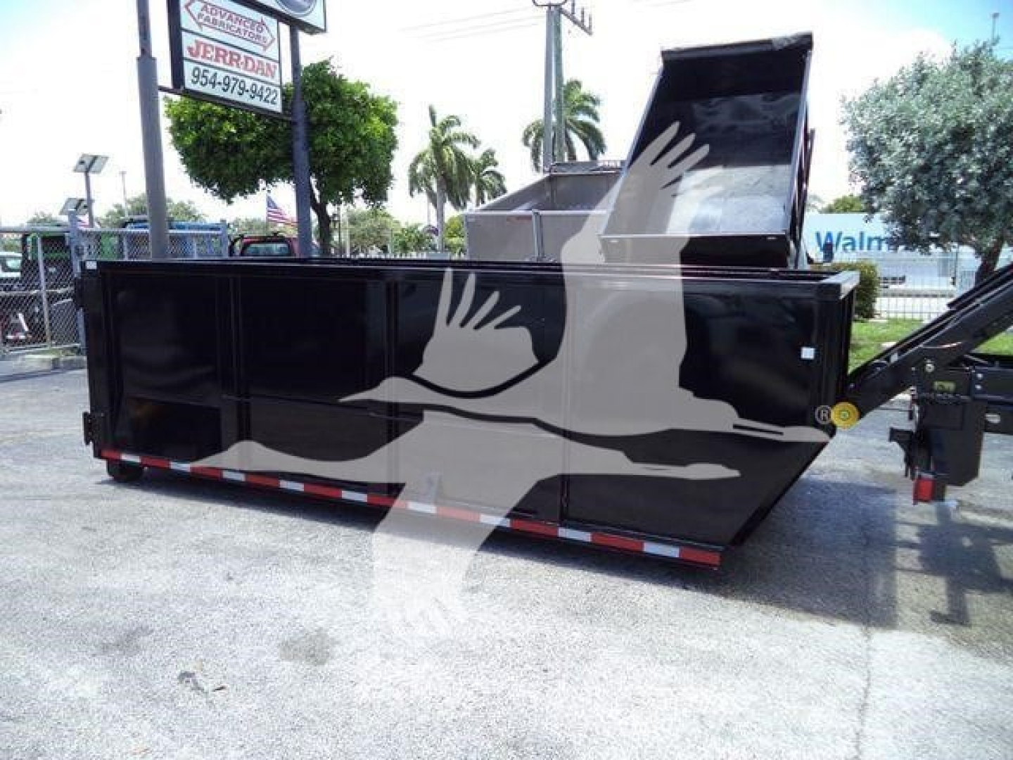 Ram 5500 SLT hooklift dumpster body trailer side view showing large black steel truck bed with open top, hydraulic hooklift mechanism on right, reflective trailer strips.