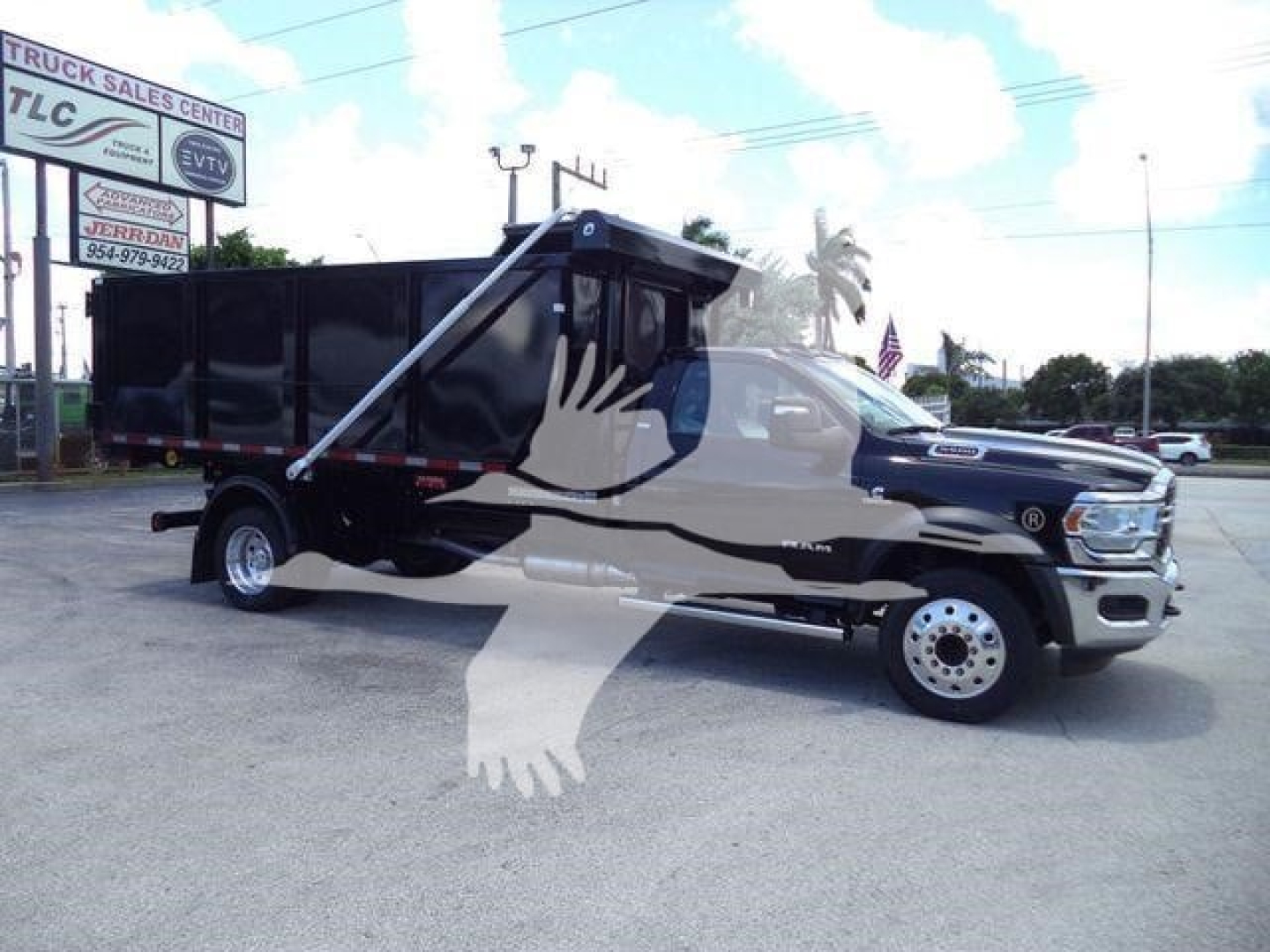 2024 Ram 5500 SLT hooklift truck in a dealership lot with a black dump body; visible signage includes ‘TRUCK SALES CENTER’ and a stylized watermark of a white hand against the truck.