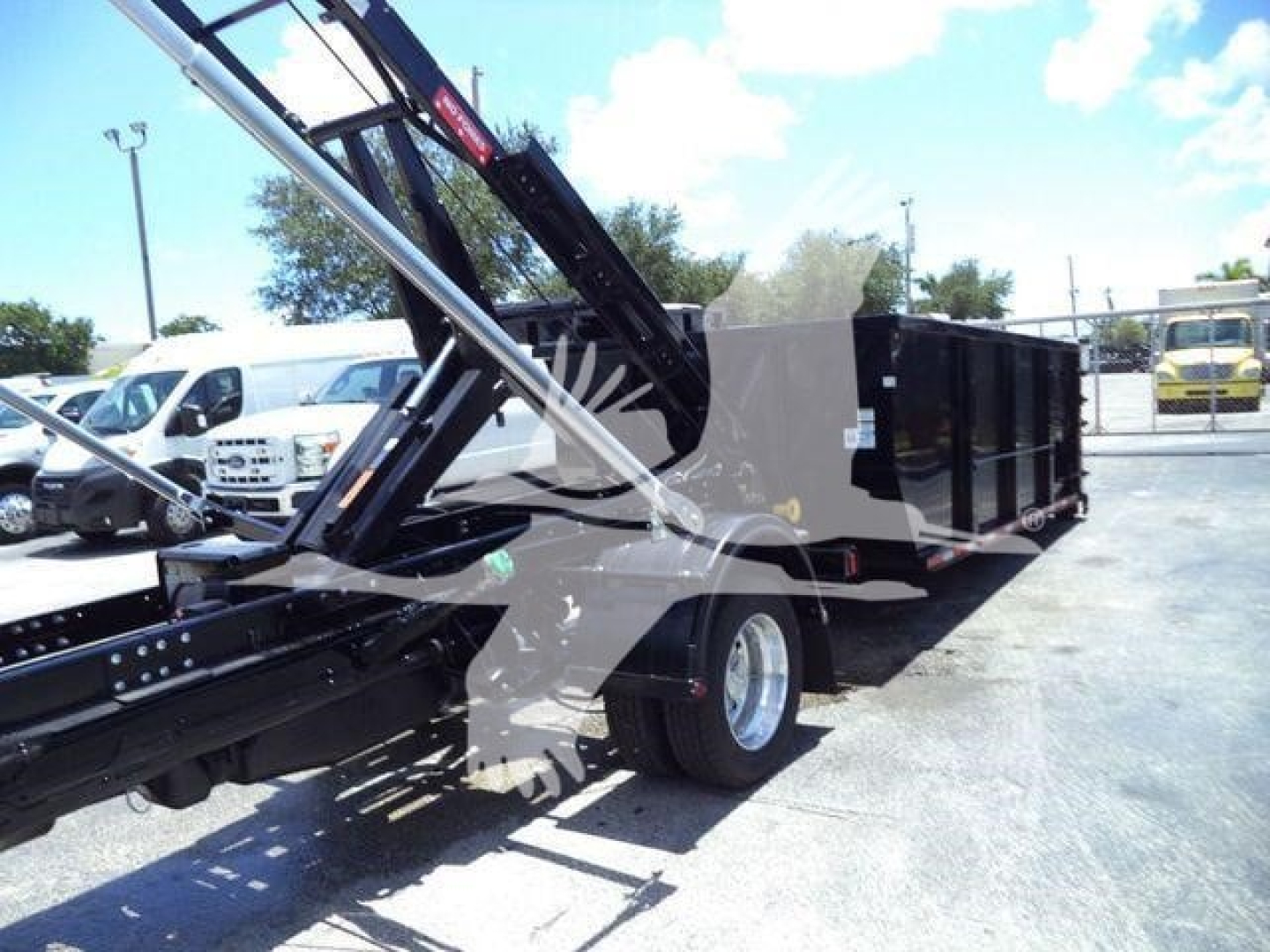 Ram 5500 SLT hooklift truck bed on a chassis with hydraulic crane arms visible and a black cargo box in the bed area.