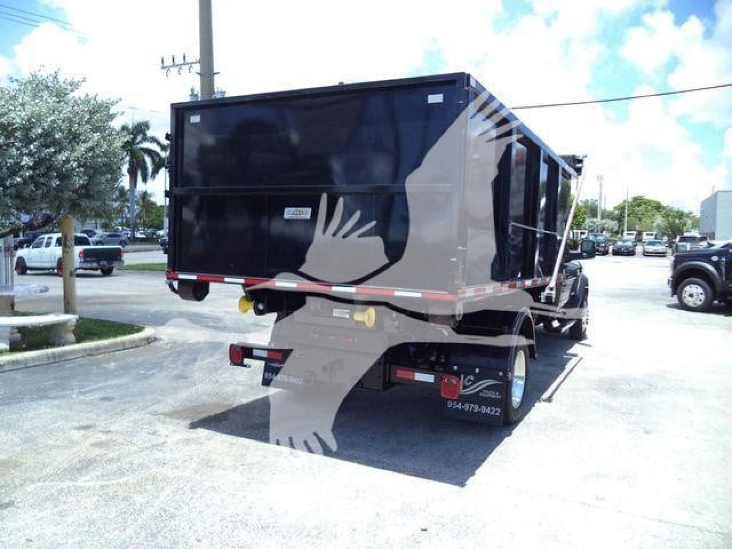 Hopper-style dump bed mounted on a Ram 5500 SLT pickup with a black container and rear bumper, viewed from the passenger side rear.