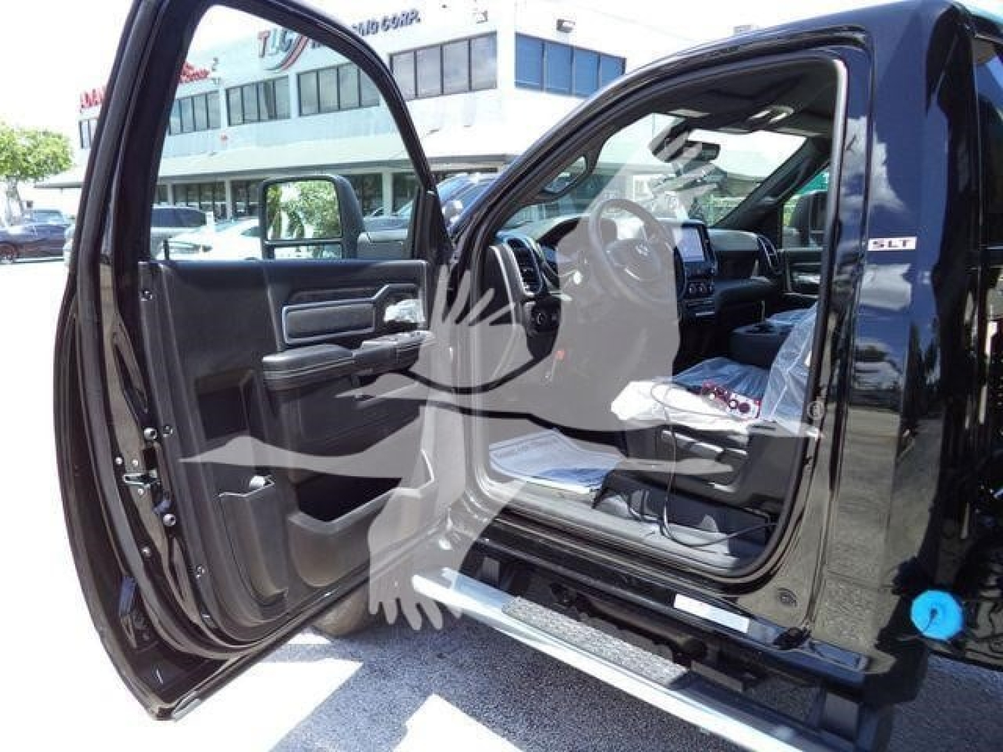 Ram 5500 SLT interior view with driver door open showing black leather and chrome trim, dashboard and infotainment screen visible.