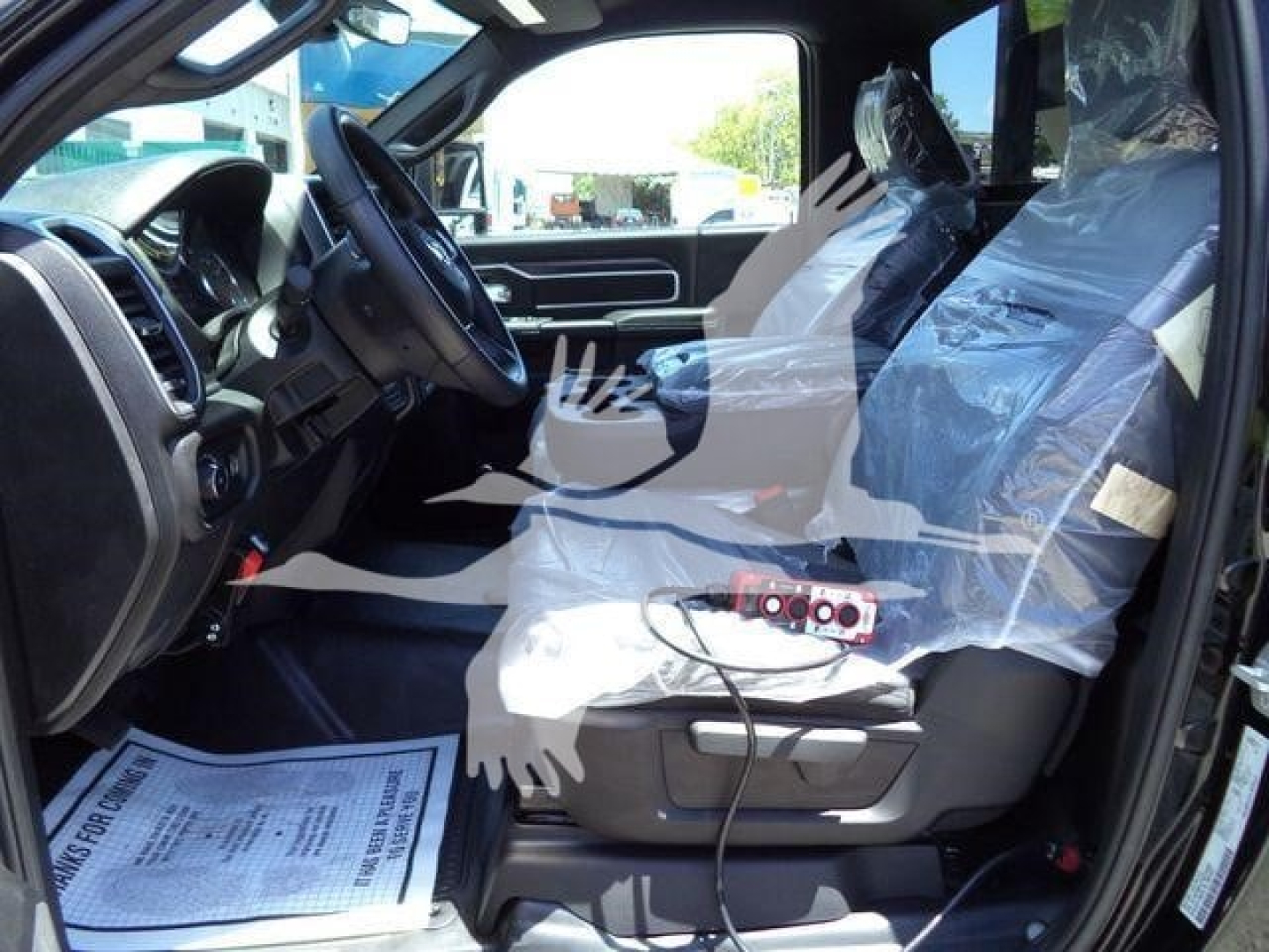 Ram 5500 SLT cab interior view showing front seats wrapped in protective plastic and dashboard area.