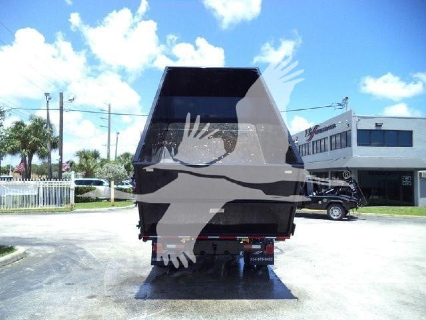 Dump trailer truck rear view showing large dump body with reflective surface and tailgate, parked in lot.