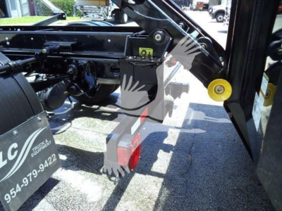 Ram truck hooklift mounting hardware with hydraulic bracket and yellow hinge, side view showing black chassis and red hitch block.