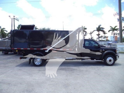 Ram 5500 chassis in-service showing hooklift bed with black dump-style container and side cab details visible.