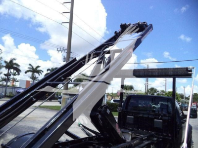 Ram 5500 Hooklift truck chassis and hoist in view with blue sky and palm trees.
