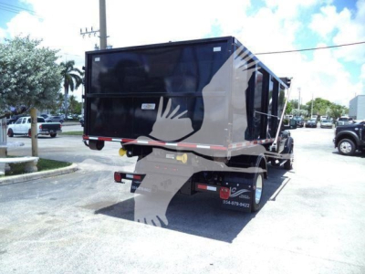 Hopper-style dump bed mounted on a Ram 5500 SLT pickup with a black container and rear bumper, viewed from the passenger side rear.