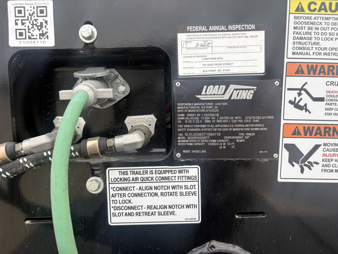 Load King trailer bay showing hydraulic hoses, fittings, and label plates including Federal inspection sticker and LOAD KING branding.