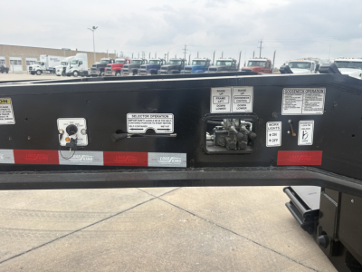 Load King trailer control panel and labels showing operation switches, gauges, and warning placards on a lowboy trailer frame.