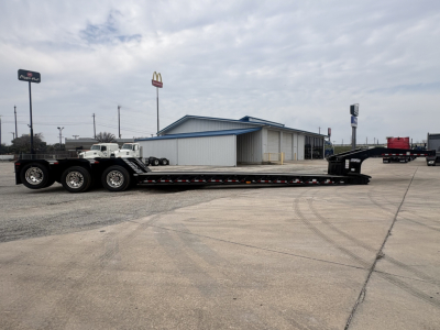 Lowboy trailer with long multi-axle deck showing Load King logo on the side and a gooseneck at the far end.