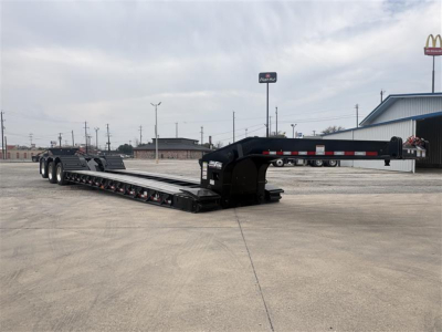Load King lowboy trailer in a parking lot showing long flatbed with multiple axles, black frame, and gooseneck hitch.