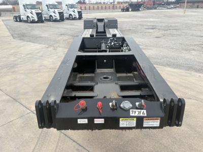 Trailer Frame of Load King lowboy showing rear connection area and labels, with red retaining pins and warning stickers.