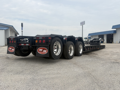 Load King lowboy trailer with multiple axles, showing rear with taillights, mud flaps, and Load King branding. Visible text includes LOAD KING on mud flaps and rear plate area.