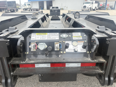 Load King trailer rear control panel and warning labels with hydraulic controls, safety decals, anti-slip paint, and coupling area in view.