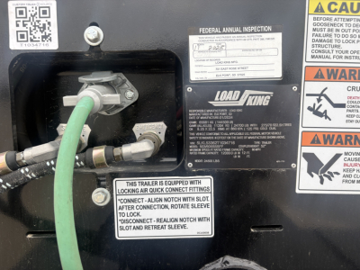 Load King trailer bay showing hydraulic hoses, fittings, and label plates including Federal inspection sticker and LOAD KING branding.