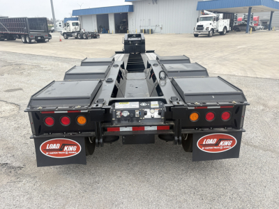 Trailer rear view showing Load King mud flaps and central hitch with multiple deck compartments and lighting. Visible labels include Load King logos on mud flaps.