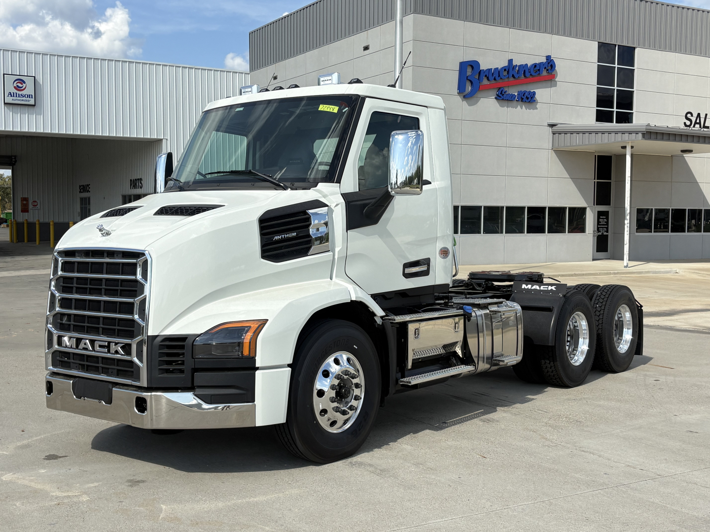 Mack AN64T conventional daycab truck in white parked outside dealership with front grille and chrome mirrors.