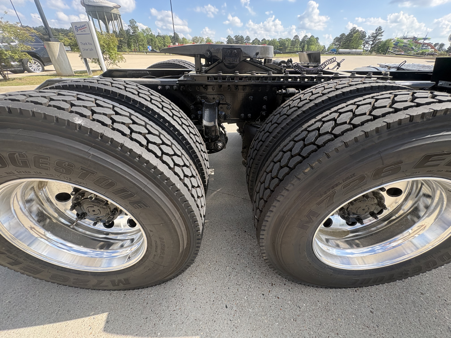 Dual rear truck wheels and chassis framing of a 2027 Mack AN64T daycab with large tires and chrome wheels, view of drive axle center.