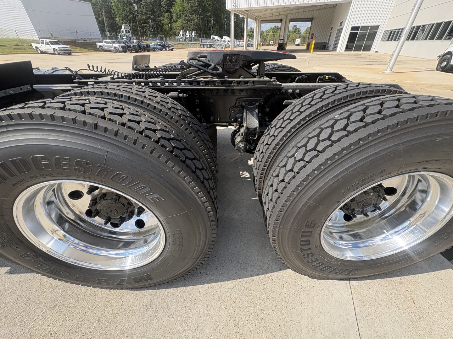 Dual rear tractor wheels with heavy-duty tires and chrome rims on a Mack AN64T cab chassis, showcasing the drive axles and suspension mounting area.